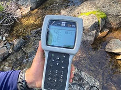 A handheld, digital multiparameter instrument displays creek measurements such as temperature and pH levels.
